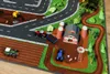 A toy farm scene with tractors, a barn, silos, and a windmill on a play mat. Produktbild-Vorschau
