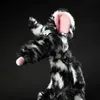 A puppet of a black and white striped creature with pink ears and a pink tongue sticking out, against a black background. Produktbild-Vorschau