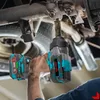 A person is using a cordless impact wrench to tighten bolts on the underside of a vehicle. Podgląd zdjęcia produktu