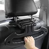 A hand is holding a black car seat organizer attached to the headrest of a car seat. Produktbild-Vorschau
