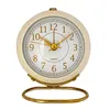 A close-up studio shot of a beige and gold alarm clock on a white background. Produktbild-Vorschau