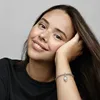 A young woman with freckles smiles as she rests her head on her hand, showing off a Pandora charm bracelet with a snowflake charm. Podgląd zdjęcia produktu