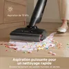 A vacuum cleaner head is shown cleaning up a spill of liquid and colorful cereal on a wooden floor, with a person's legs and feet visible in the background. Produktbild-Vorschau