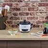 A Russell Hobbs mini rice cooker is shown on a kitchen counter with a bowl of rice, chopsticks, soy sauce, and chili peppers. Náhľad obrázku produktu