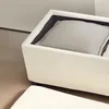 A close-up view of a beige cord-optic storage bench with a gray cushion inside, placed on a beige carpeted floor next to a light gray wall. Podgląd zdjęcia produktu