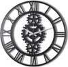 A black metal wall clock with Roman numerals and gears. Náhľad obrázku produktu