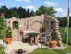A rustic outdoor seating area with a brick wall, table, and benches. Produktbild-Vorschau