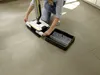 A person is kneeling on a tiled floor, assembling or cleaning a cordless floor cleaner. Produktbild-Vorschau