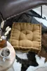 A floor cushion is placed on a cowhide rug next to a coffee table with a cup of coffee and some dried flowers. Podgląd zdjęcia produktu