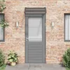 A front door with a canopy, flanked by windows and plants, set against a brick wall. Náhled obrázku produktu