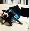 A hand is holding a black and blue vacuum cleaner on a beige sofa with black pillows. Podgląd zdjęcia produktu