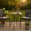 A small round bistro table with two chairs on a patio, set for an evening drink. Produktbild-Vorschau