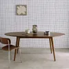 A dining table with chairs in a room with grid-patterned wallpaper. Produktbild-Vorschau