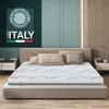 A mattress is displayed on a bed in a bedroom setting, with decorative pillows and bedside tables. Produktbild-Vorschau