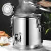 A stainless steel food warmer with steam rising from it, a hand is opening the lid, and a glass of milk and bread are on the side. Voir les images du produit