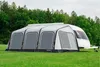 An inflatable caravan awning is set up on a grassy field with trees in the background. Produktbild-Vorschau