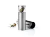 A stainless steel nutmeg grater with a glass top filled with nutmegs, placed on a white background with a sprig of rosemary and a single nutmeg to the side. Another part of the grater is lying on its side in the background. Produktbild-Vorschau