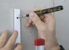 A person is using a marker to mark a hole in a metal strip attached to a concrete wall. Produktbild-Vorschau