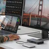 A person's hands are visible using a laptop and mouse, connected to a docking station and external hard drive, with multiple monitors displaying images of the Golden Gate Bridge. Produktbild-Vorschau