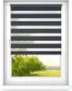 A window with a roller blind partially covering the view of a green landscape. Voir les images du produit