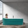 A woman is sitting in an inflatable bathtub in a modern room with large windows. Náhled obrázku produktu