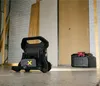 A work light and a toolbox are on a concrete floor in what appears to be a construction or workshop setting. Produktbild-Vorschau