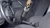 A hand is using a cordless vacuum cleaner inside a car, near the driver's seat and center console. Produktbild-Vorschau