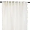 A close-up view of a cream-colored curtain with pom-pom trim hanging from a curtain rod. Podgląd zdjęcia produktu