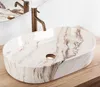 A marble-patterned vessel sink with a bronze faucet on a wooden countertop. Náhľad obrázku produktu