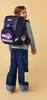 A young girl wearing a backpack and jeans, looking over her shoulder. Produktbild-Vorschau