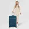 A woman stands next to a teal suitcase. Anteprima dell’immagine prodotto