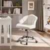 A white office chair with a unique shell-like design is placed on a textured tan rug in a room with a bookshelf and a desk. Produktbild-Vorschau
