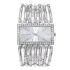 A silver-colored women's watch with a rectangular face and a crystal-embellished bezel, set against a white background. Produktbild-Vorschau