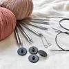 A collection of knitting needles and yarn on a textured white surface. Produktbild-Vorschau