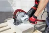A person is using a grinder with a dust collection system to cut a concrete block. Produktbild-Vorschau