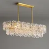 A rectangular chandelier with multiple tiers of clear, crystal-like elements hanging from a gold frame, suspended from a ceiling. Anteprima dell’immagine prodotto