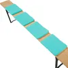 A long wooden bench with four turquoise seat cushions placed on it, shown from a diagonal angle against a white background. Produktbild-Vorschau