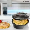 A Bomann waffle maker is shown in use, with freshly made heart-shaped waffles on a plate next to it. The background is a blurred kitchen scene. Náhled obrázku produktu
