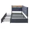 A dark gray upholstered bed frame with a built-in headboard shelf and two pull-out drawers is shown against a white background. Náhled obrázku produktu