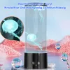 A jellyfish lamp with a black base, set against a blurred background of water and pink rocky formations. There are also some floating spheres. Produktbild-Vorschau