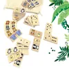 A collection of dominoes with animal illustrations and standard domino dots, arranged on a white background with some green foliage graphics. Produktbild-Vorschau