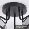 A close-up view of the ceiling mount and arms of a black chandelier with glass shades. Produktbild-Vorschau