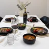 A table set for a meal with plates, wine glasses, a bottle of wine, and food. Voir les images du produit