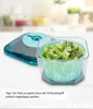A salad spinner with chopped lettuce inside, placed next to its lid, on a blurred kitchen background. Produktbild-Vorschau