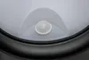 A close-up view of a motion sensor on a white and black outdoor light fixture. Produktbild-Vorschau