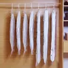 Several vacuum-sealed garment bags hang on a wooden rod inside a closet. Anteprima dell’immagine prodotto