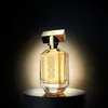 A bottle of Hugo Boss The Scent for Her perfume is displayed on a dark pedestal against a dark, spotlighted background. Anteprima dell’immagine prodotto