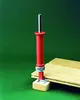 A red and silver magnet nail holder is shown in use on a piece of wood. Produktbild-Vorschau