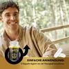 A man smiling outdoors, with a product bottle and capsules visible. Produktbild-Vorschau