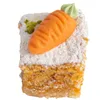 A single slice of carrot cake decorated with a marzipan carrot and green icing. Produktbild-Vorschau